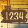 Rustic metal raccoon head address sign mounted on cabin wall