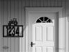 Metal house number sign with tractor accent mounted outdoors.